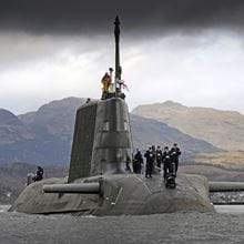 Royal Navy's HMS astute submarine sailing from clyde under moody skies with darkened and shadowed mountains in background