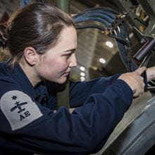 closeup sideview image of brown-haired uniformed Air Engineering Technician with role badge showing on shoulder working on equipment