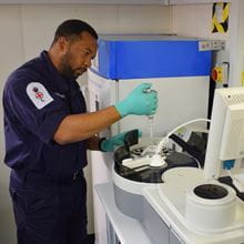 blue uniformed dark haired medical specialist working with equipment in clinical setting