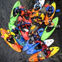 A group of Kayakers in colourful kayaks gather together