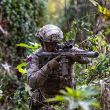 Commando in forest taking aim with an L400