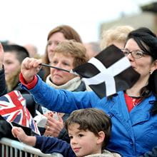 Woman in blue coat stood behind a small boy waving a Cornish flag