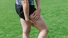 person with hands on hamstring