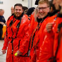 A team of Royal Navy sailors in orange training suits.