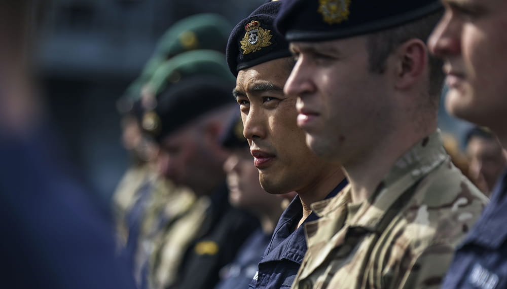 dressed in fatigues and green berets royal marines stand in line in sunny conditions