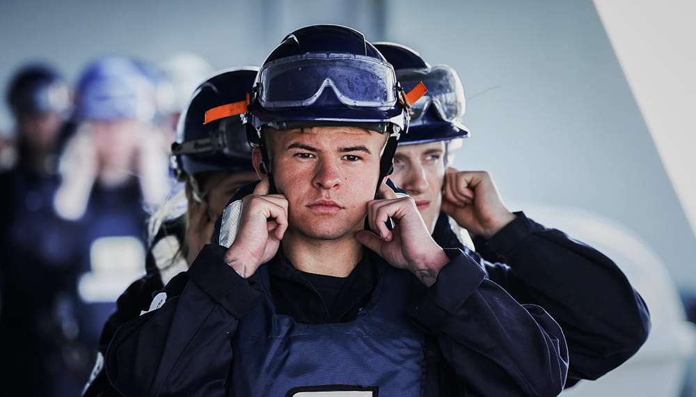 head on image of crewmembers in navy blue uniforms and helmets in line