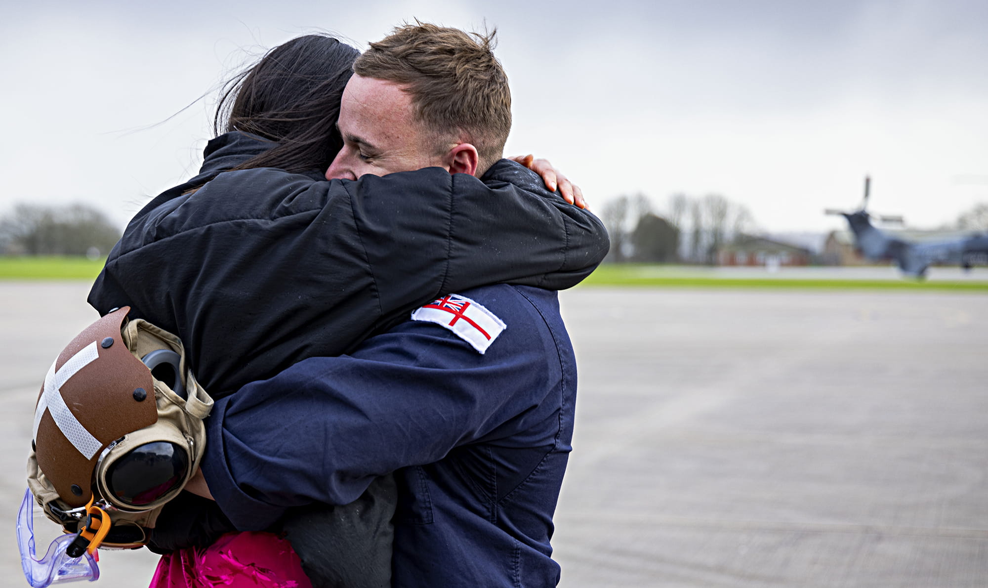 uniformed fleet air arm crew member hugging loved one on air strip
