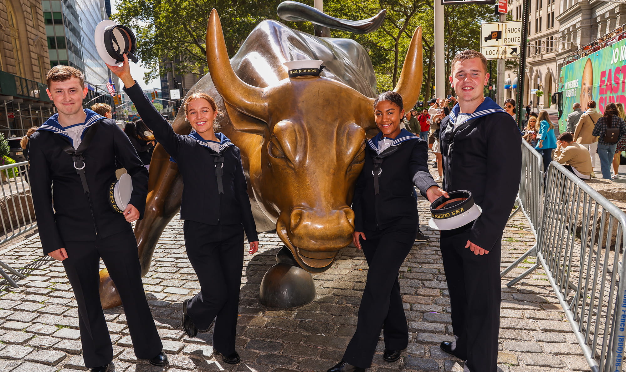 four uniformed royal navy personnel pose for picture at the famous bull of wall street in new york city