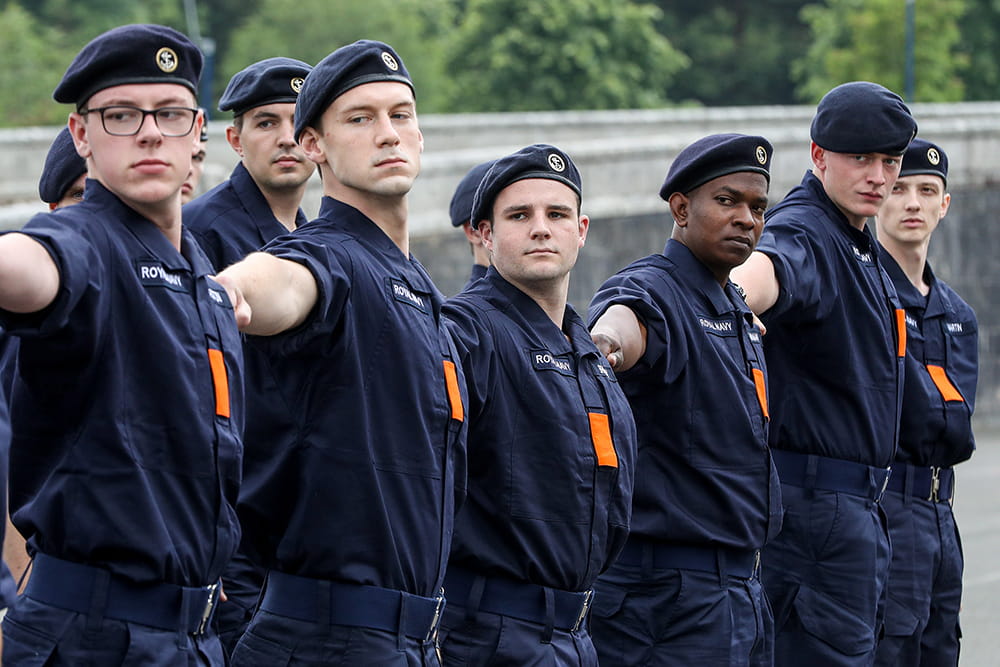 ratings wearing blue uniforms with orange badges on chest on parade training lining up at arms length looking right
