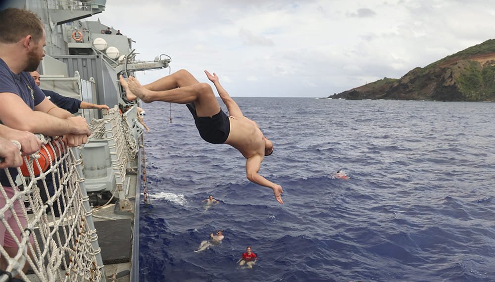 Surgeon Lieutenant attempt a back flip during Hands to bathe when the ship is at anchor in Bounty Bay in Pitcairn Island