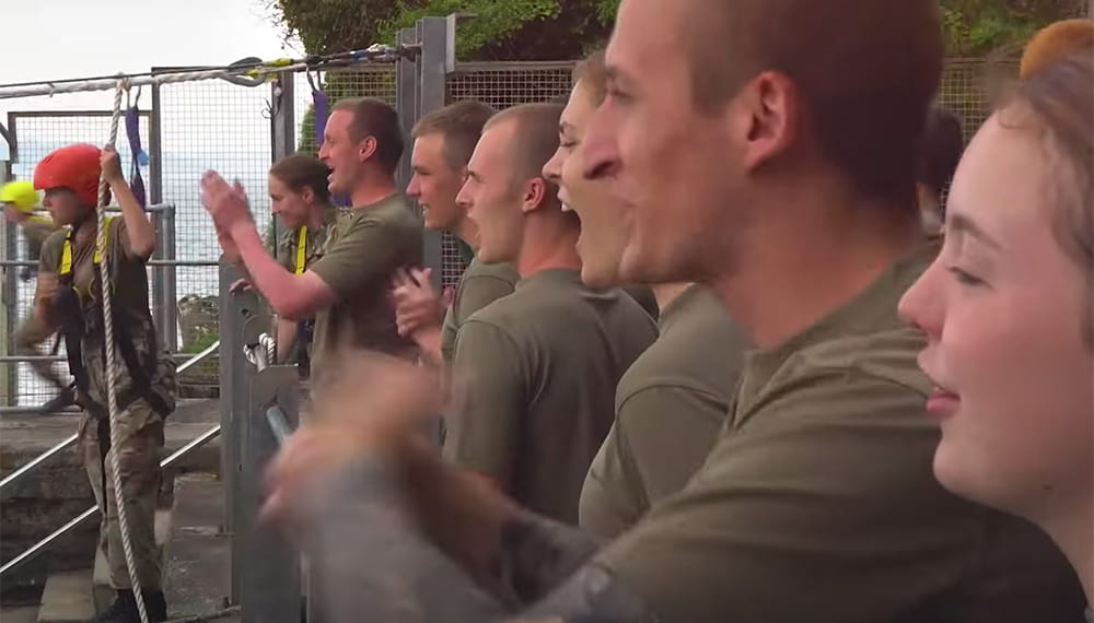Royal Navy reservists wearing khaki t-shirts cheering on colleagues during training