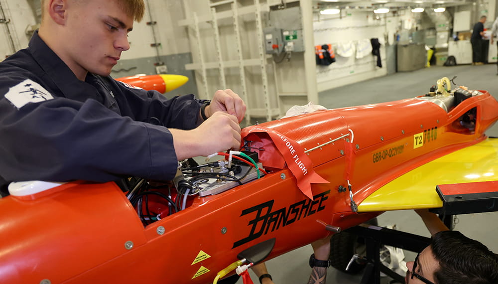 Young engineers work on an orange drone in a workshop