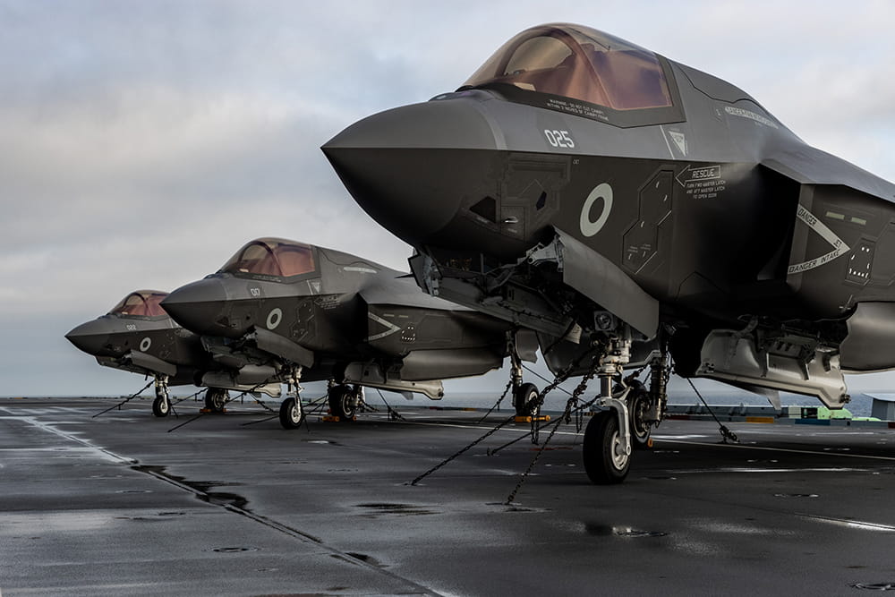 Three F-35 Lightning jets line-up on the deck of an aircraft carrier