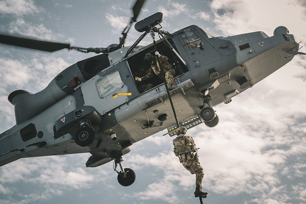 Royal Marine abseils out of a Wildcat helicopter in flight