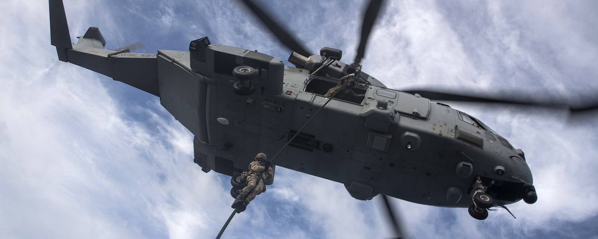 Marine performing fast rope training from a Merlin