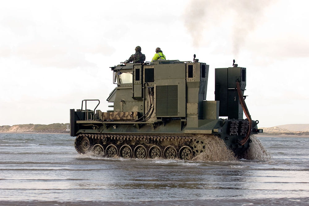 Side-on view a beach recovery vehicle driving through shallow water