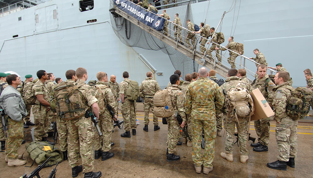 Royal Marine commandos wait on quay and walk up the gangplank onto RFA Cardigan Bay