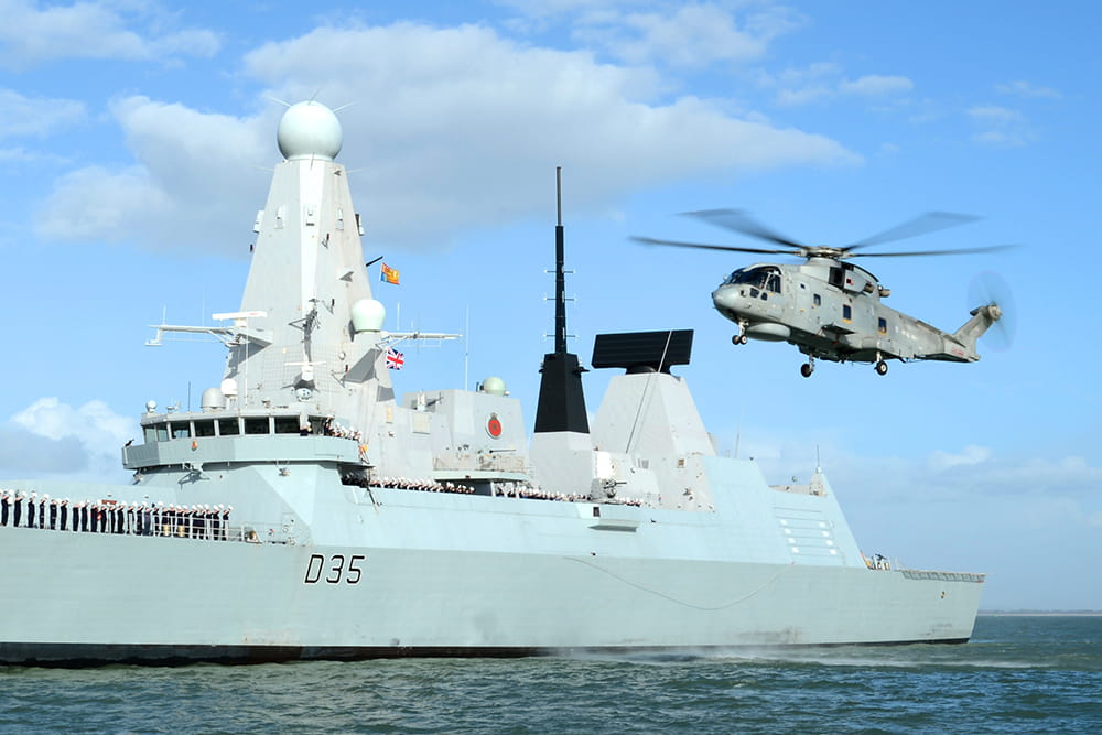 Royal Navy Merlin helicopter flies alongside HMS Dragon