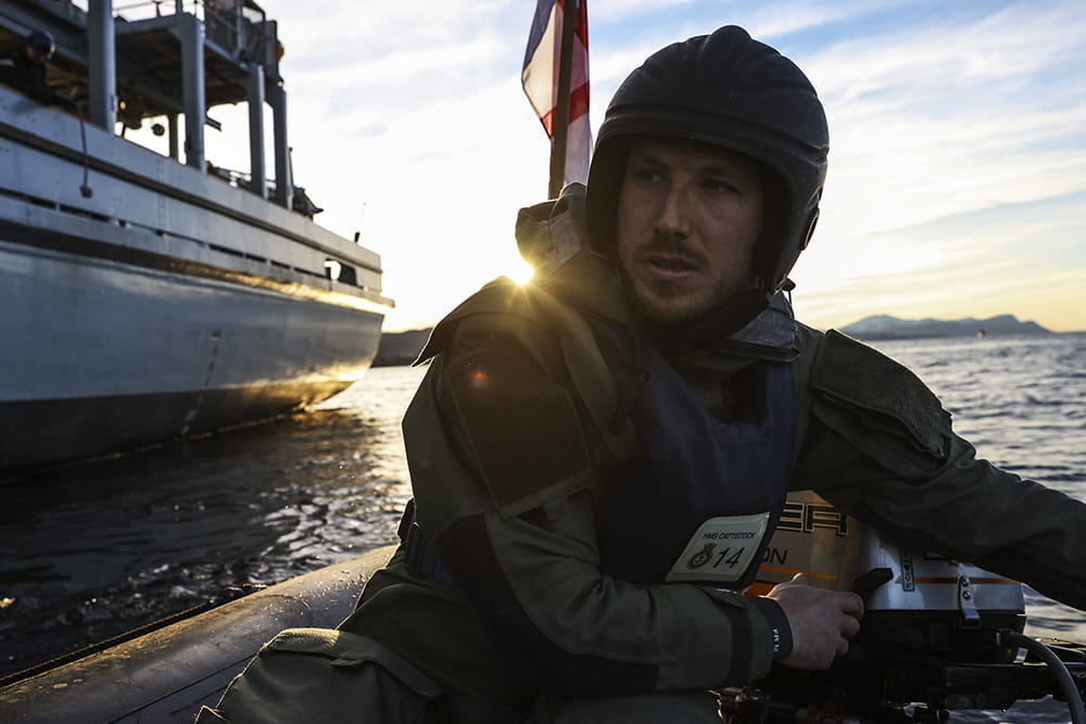 Royal Navy sailor mans the outboard engine of an inflatable boat