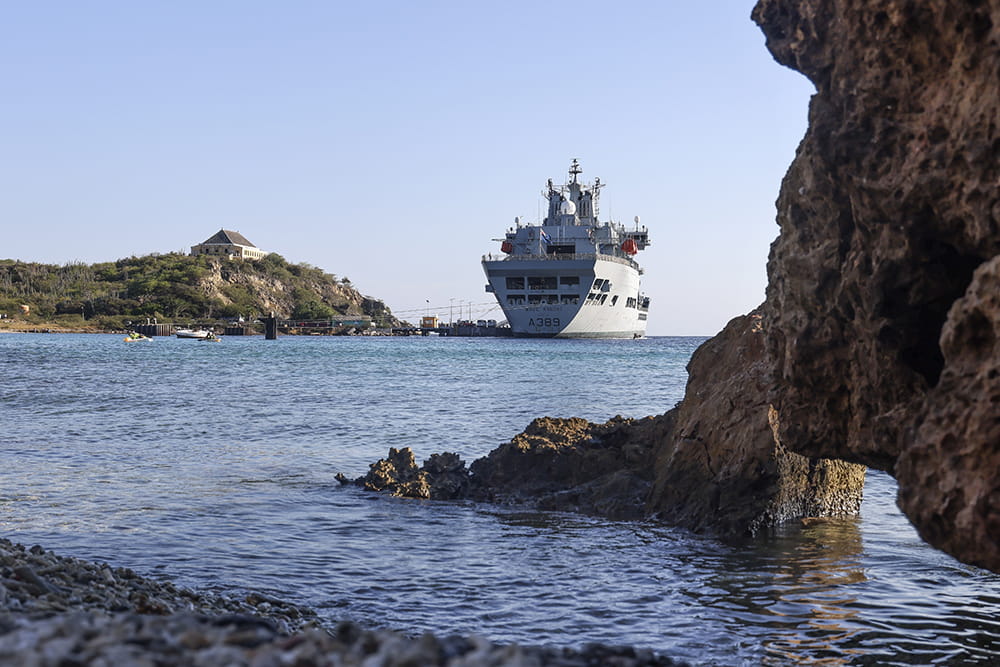 RFA Wave Knight in the distance from a rocky coastline