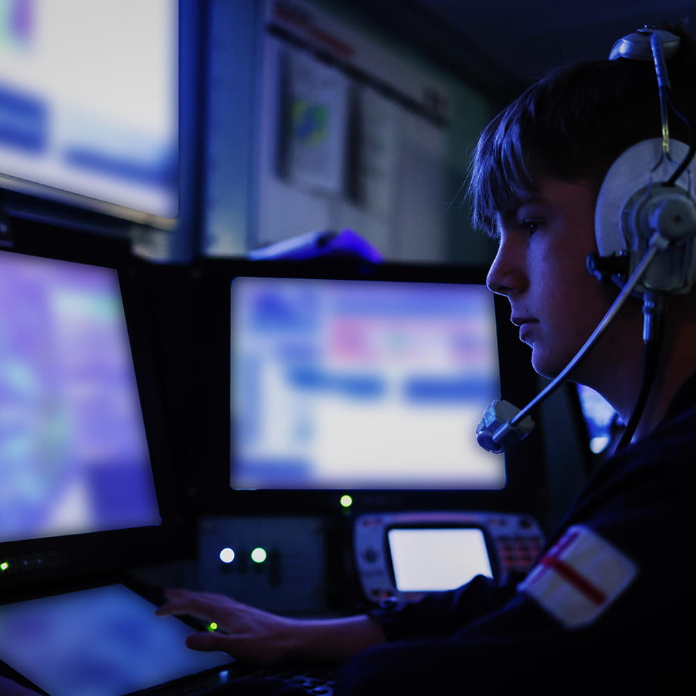 Royal Navy sailor looks at an array of monitors