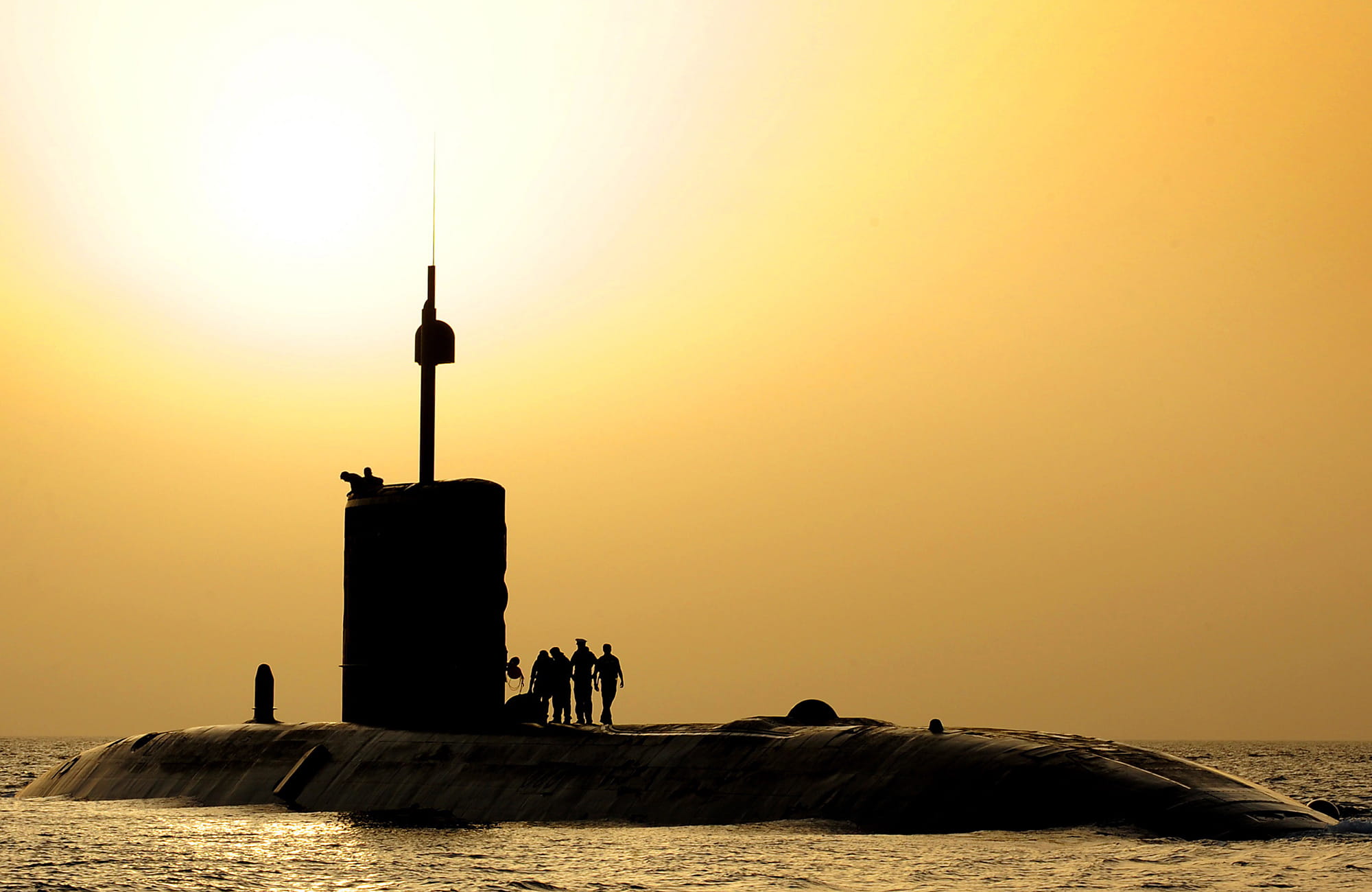 Silhouette of Royal Navy submarine at sunset with a yellow sky background