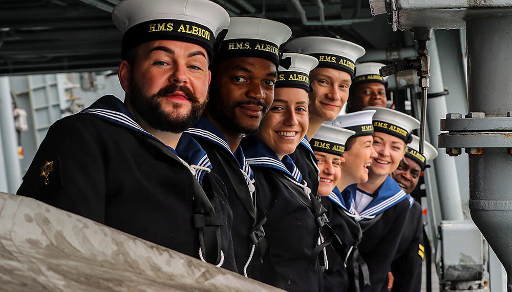 Sailors of HMS Albion standing in a row smiling at camera