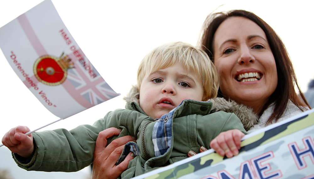 Mother and son with flags and banners welcoming home