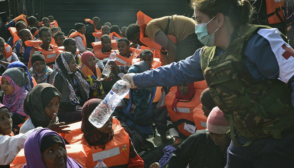 Royal Navy medic hands out water to rescued civilians