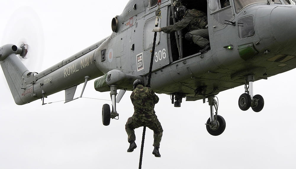 Royal Navy personnel taking part in boarding party fast rope training from a helicopter