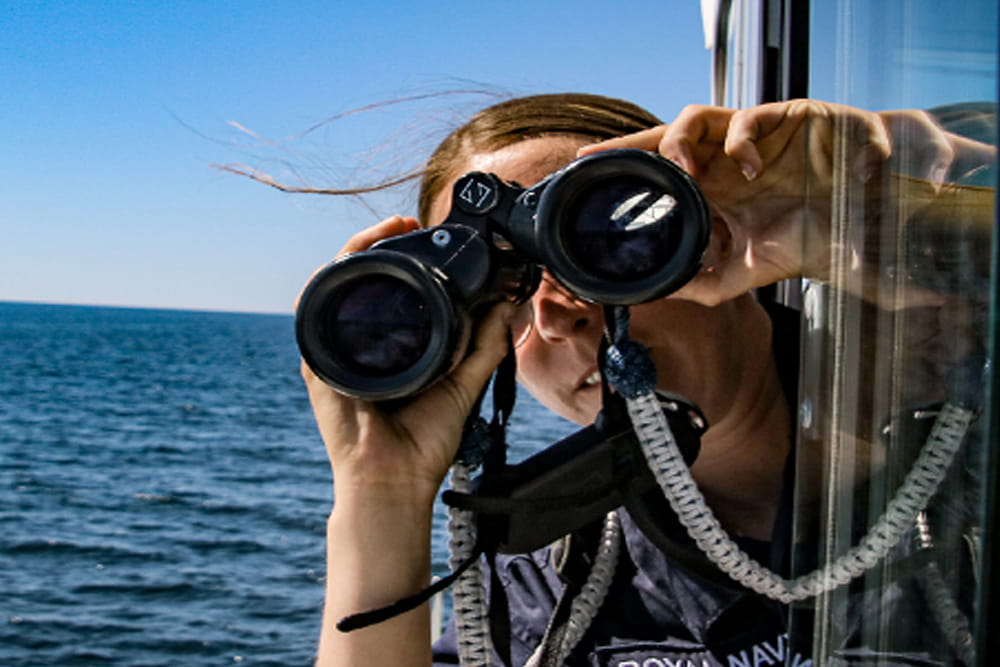 URNU student at sea looking through binoculars 