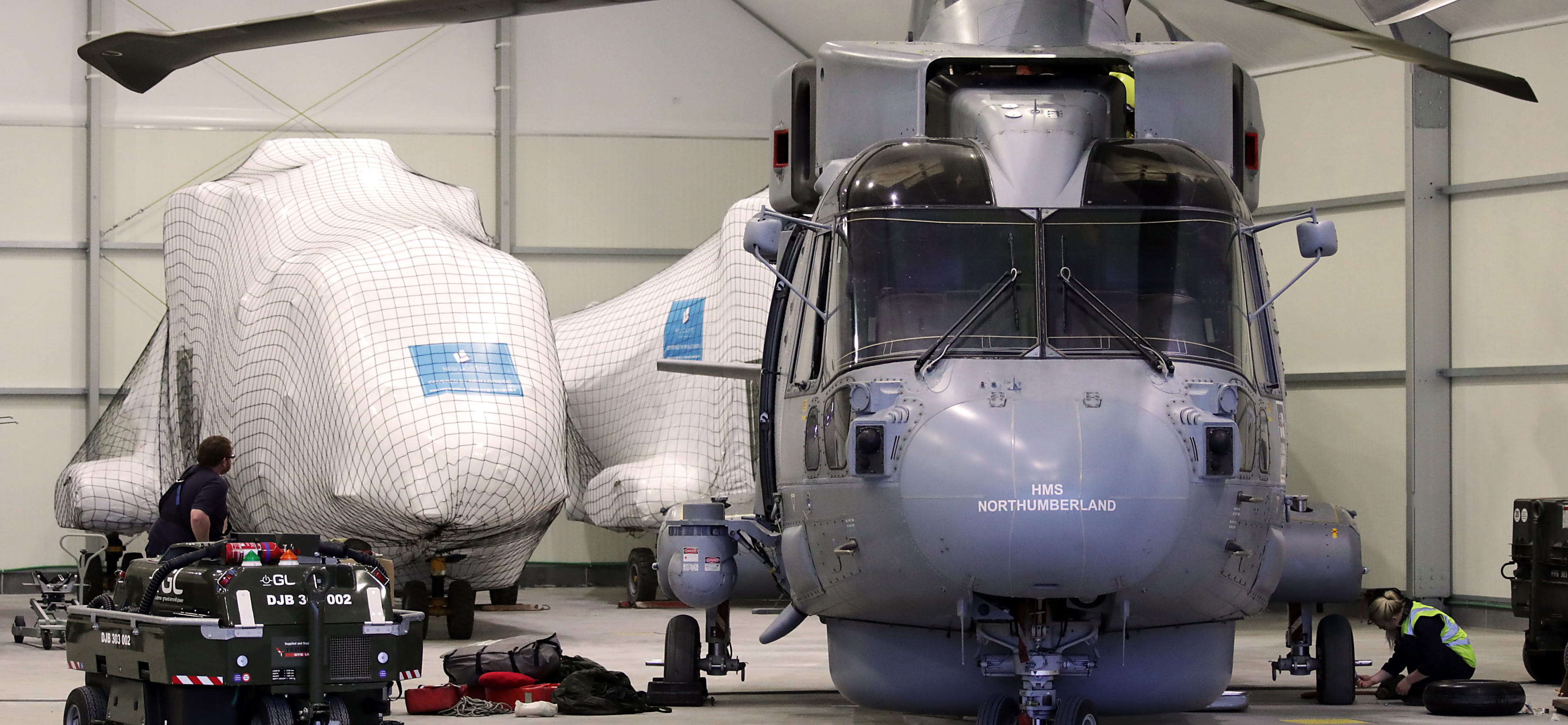 AIR ENGINEER TECHNICIANS WORKING INSIDE A HANGER IN CATANIA ON A MERLIN READY FOR FLYING IN THE MORNING