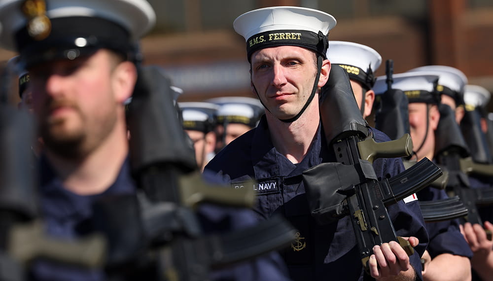 Royal Navy sailors in line with guns resting on their shoulders
