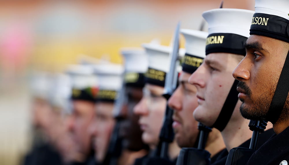 Royal Navy sailors in ceremonial uniforms stand in line